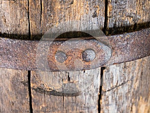 Fragment of a riveted metal hoop on an old wooden barrel