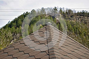 Fragment of the roof covered with flexible shingles in the form of honeycomb on the background of the mountain photo