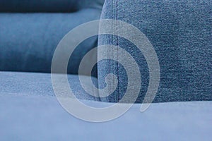 Fragment of the seat, back and armrest of the blue sofa.