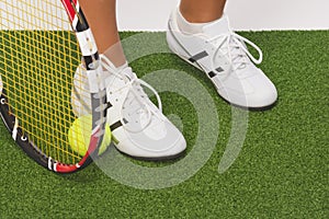 Fragment Shot of Legs of Caucasian Female Tennis Sportswoman Holding Racket with Ball Tightly Underneath, Standing On Artificial