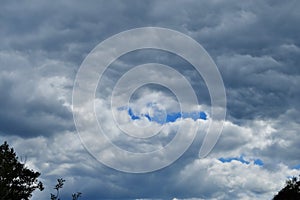 A fragment of the sky covered with thick rain clouds with a glimmer of blue sky