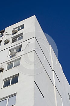 A fragment of a tall residential building against a clear blue sky
