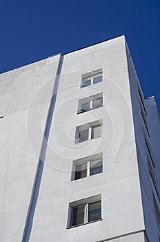 A fragment of a tall residential building against a clear blue sky