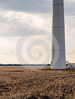 Fragment of tower of Eletric power generator wind turbine with rotating blades at sunset against cloudy sky. Close-up. Adyghe wind