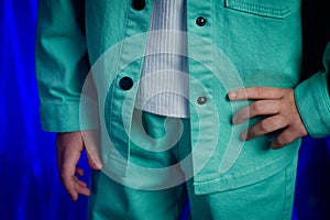 A fragment of underage clothes of a denim jacket and turquoise trousers with a white T-shirt on the model