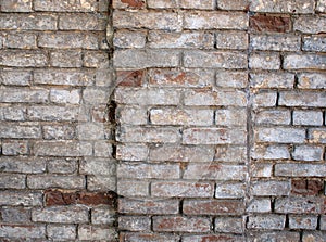 Fragment of a wall of an old red brick with white coating