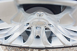 Fragment of white modern car with wheel on steel disc, closeup photo.