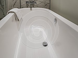 A fragment of a white oval acrylic bathtub.