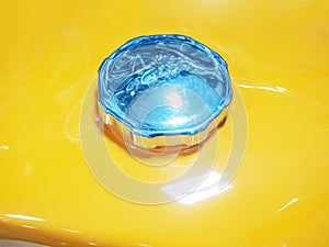 Fragment of a yellow gas tank from a motorcycle with a metal cover. Closeup photo