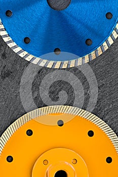 Fragments of a blue and yellow diamond cutting wheel are located against the background of gray granite. Close-up. Vertical image