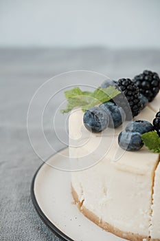 Fragments of classic cheesecake with fresh berries on a gray background.