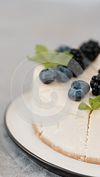 Fragments of classic cheesecake with fresh berries on a gray background.