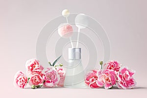 Fragrance diffuser and carnation flowers decor on pink background