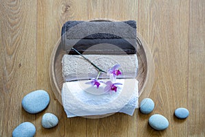 Fragranced towels and ayurveda orchids over stones and wooden background