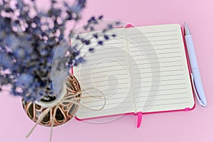 Look at opened paper notepad in a pink cover through fragrant bouquet of dry lavender with small purple flowers