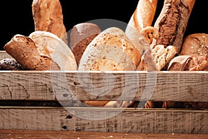 Fragrant bread on the table. Food concept in a wooden box on black background