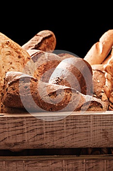 Fragrant bread on the table. Food concept in a wooden box on black background