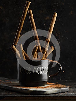 Fragrant cinnamon sticks in a black cup on a dark background. Tea, coffee, alcoholic drinks, confectionery, pastries. Eastern
