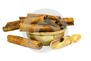 Fragrant cinnamon sticks in a wooden cup with a spoon for spices isolated on a white background. Collection of spices and herbs