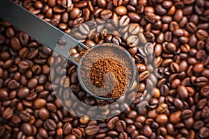 On the fragrant coffee beans is a black long measuring spoon, which is filled with ground coffee. The view from the top