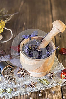 Fragrant dried healing herbs for therapy and spicy spices. On the table in a mortar purple basil, tansy, pepper, chili and