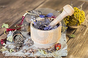 Fragrant dried healing herbs for therapy and spicy spices. On the table in a mortar purple basil, tansy, pepper, chili and
