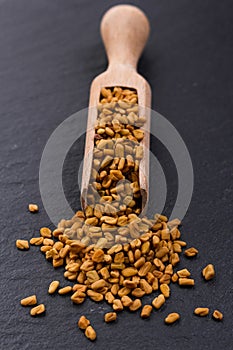 Fragrant grains of fenugreek on a rustic background