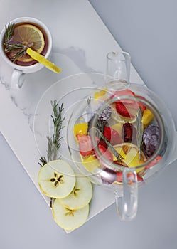 fragrant healing tonic berry tea in a transparent teapot with lemon rosemary strawberry orange mango blackberry