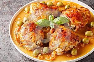 Fragrant hot ruddy chicken thighs baked with green olives close-up in a plate. Horizontal