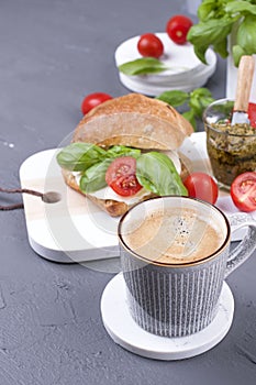 A fragrant morning coffee and a sandwich with mozzarella and basil for breakfast. Tasty and healthy food. Italian lunch. Copy
