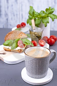 Fragrant morning coffee and a sandwich with mozzarella, pesto sauce with basil for breakfast. Tasty and healthy food. Italian