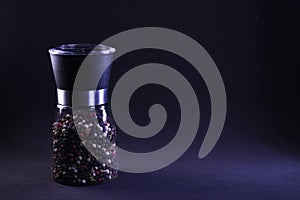 Fragrant multicolor peppercorns in a pepper shaker on a black background