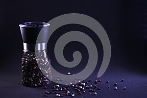 Fragrant multicolor peppercorns in a pepper shaker on a black background
