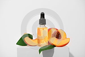 Fragrant peach essential oil on a white stand. An aromatic fruit spa oil for skin care. Alternative homeopathic medicine product