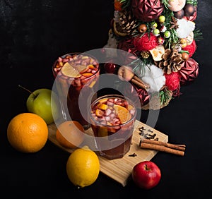 Fragrant spicy traditional drink in a glass goblet, mulled wine, with a Christmas tree, spices and fresh fruits