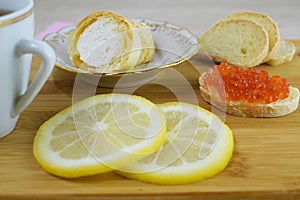 Fragrant tea with lemon and a sandwich with red caviar.