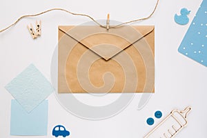 Frame of baby accessories and an envelope on a white background, top view. Children`s background. Mockup, copy space.
