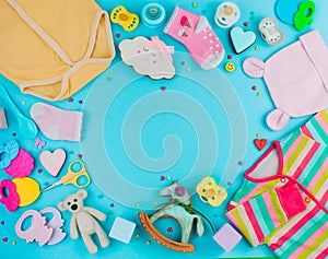 Frame of baby clothes, toys and accessories on blue background w