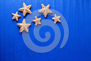 Frame from big and small golden decorative stars on electric  blue paper textured background.