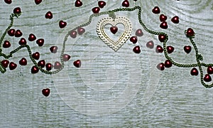 Frame border of gold and red hearts on light wooden background.