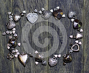Frame border of Hearts beads on old dark wooden background