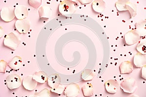 Frame border made of white roses petals and red confetti on pink background. Happy Valentines Day, Mothers Day, birthday greeting