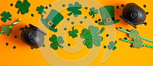 Frame border of shamrock four leaf clovers, Irish elf hats, pots of gold, confetti. Saint Patrick`s day symbols on orange