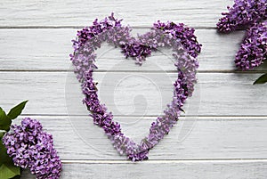 Frame of branches and flowers of lilac in the shape of a heart