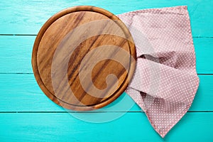 Frame of brown round pizza cutting food board on polka dots tablecloth. Blue wooden background in restaurant. copy space. Mock up.