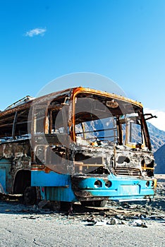 The frame of the burnt bus on the mountain road in Pakistan