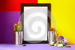 Frame with cacti in metal cans on light violet floor and bright red yellow and violet background for copyspace