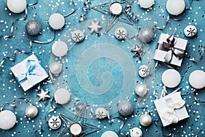 Frame of christmas decoration, gift box, confetti and silver sequins on vintage blue table top view. Flat lay. Party mockup.