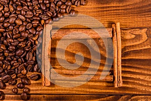 Frame of cinnamon sticks, coffee beans and star anise on wooden table