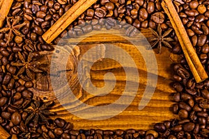 Frame of coffee beans, star anise and cinnamon sticks on wooden table
